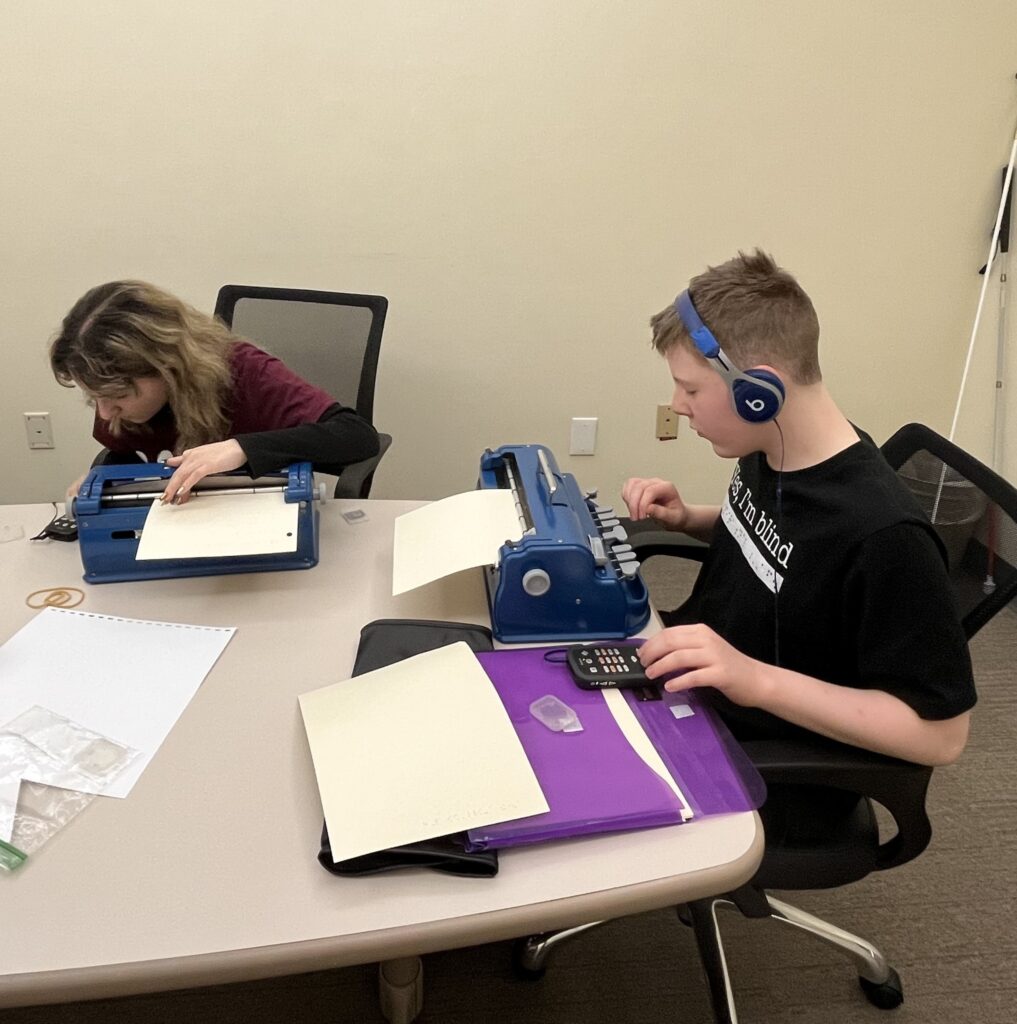 two Braille Challenge contestants sit at a table working on their contests